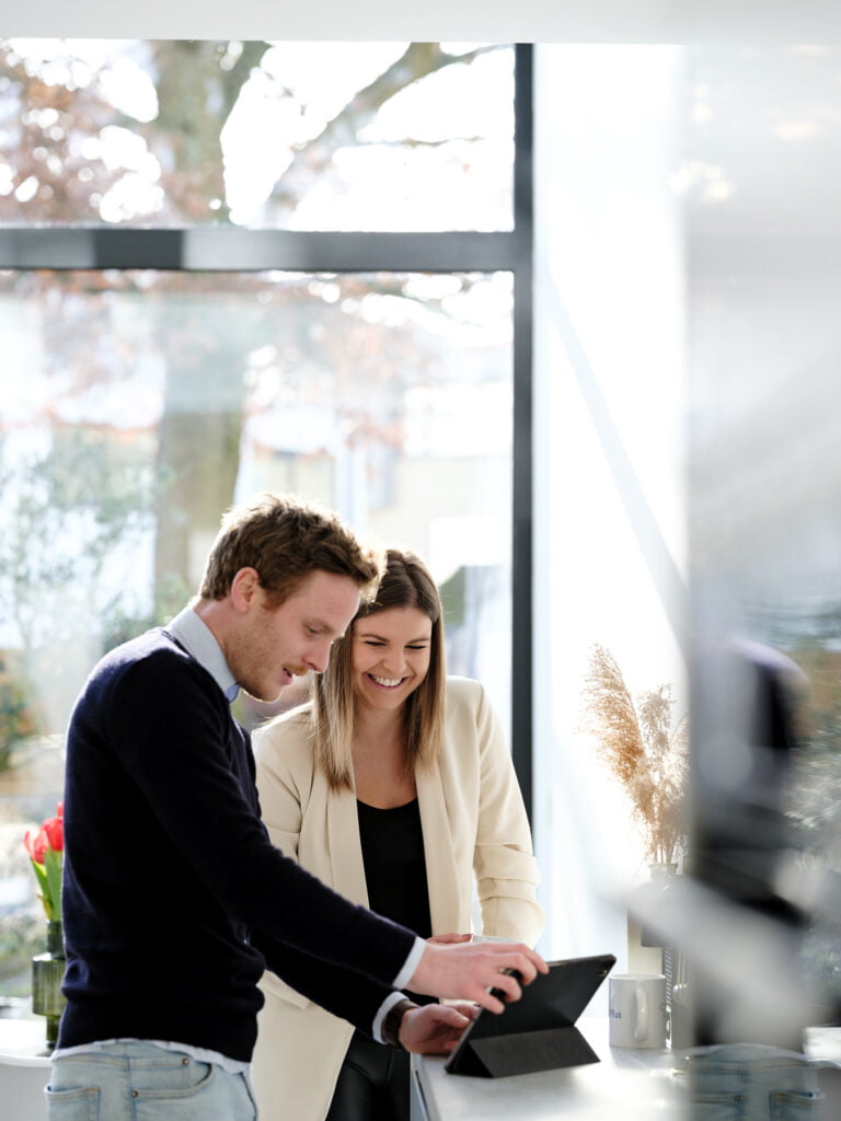 Vrolijke man en vrouw voeren een plaatsbeschrijving uit op de iPad